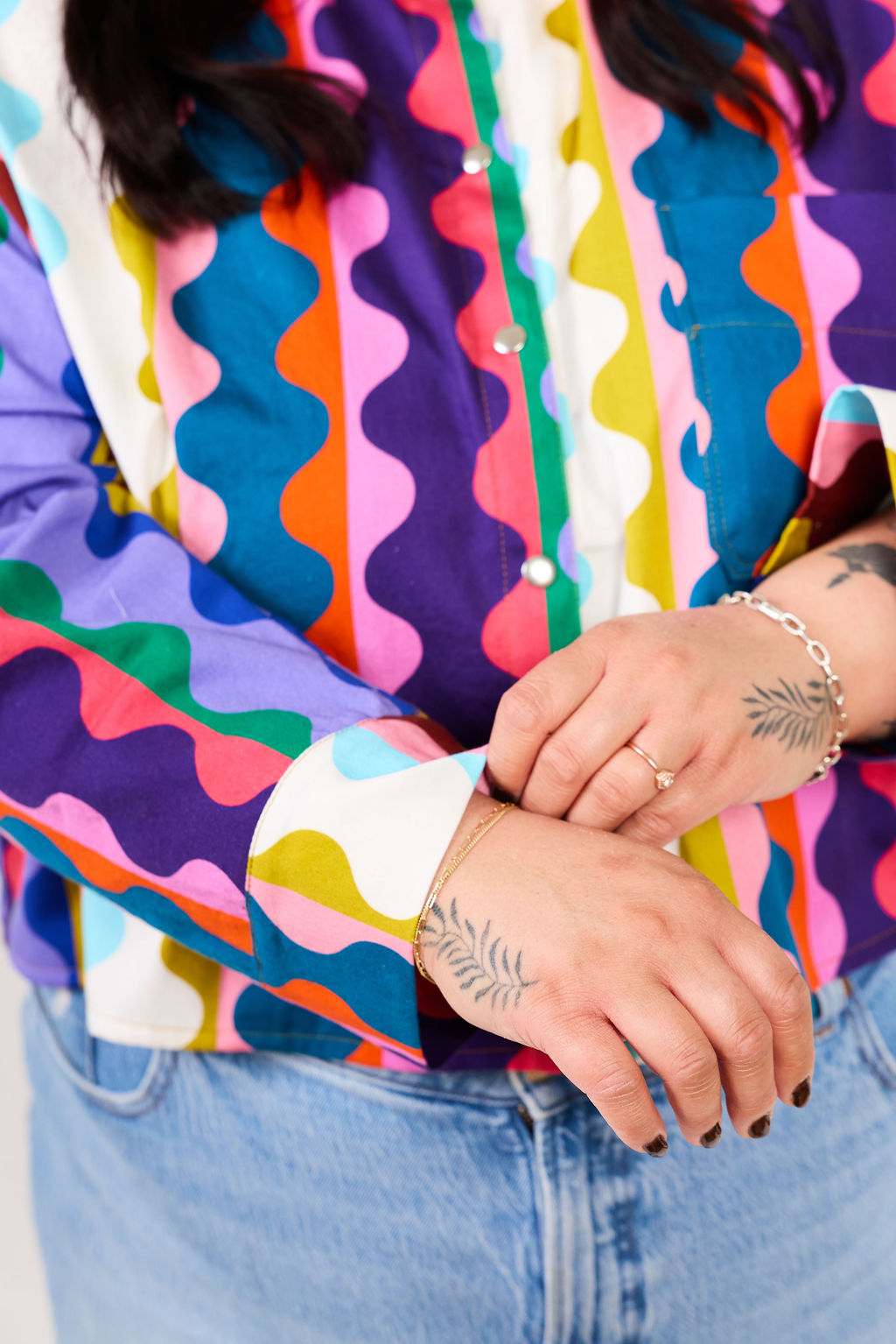 Person wearing a colorful patterned shirt with a wide cuff. 
