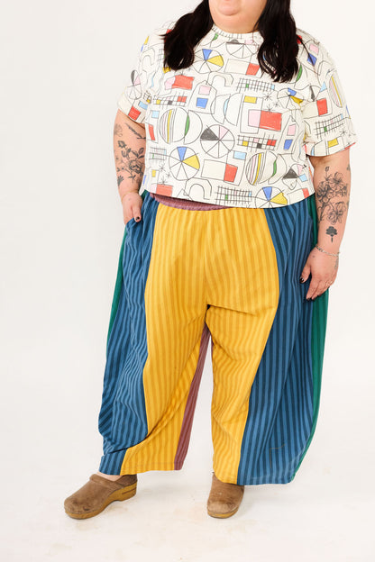 Person wearing a colorful patterned shirt and multicolored pants on a white background