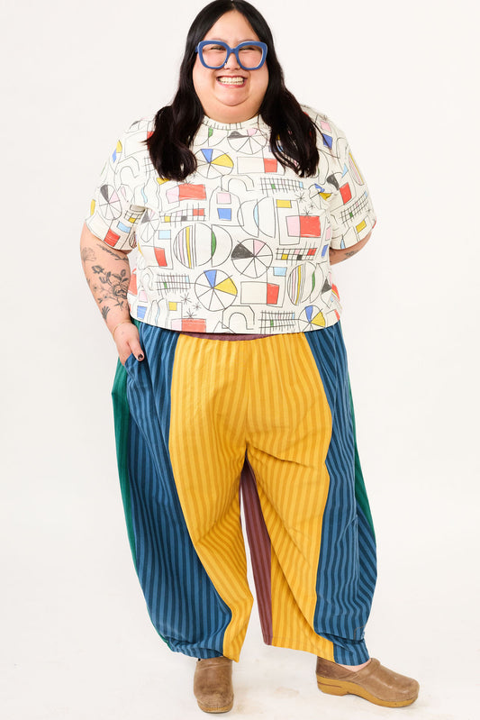 Person wearing a colorful patterned shirt and multicolored pants on a white background