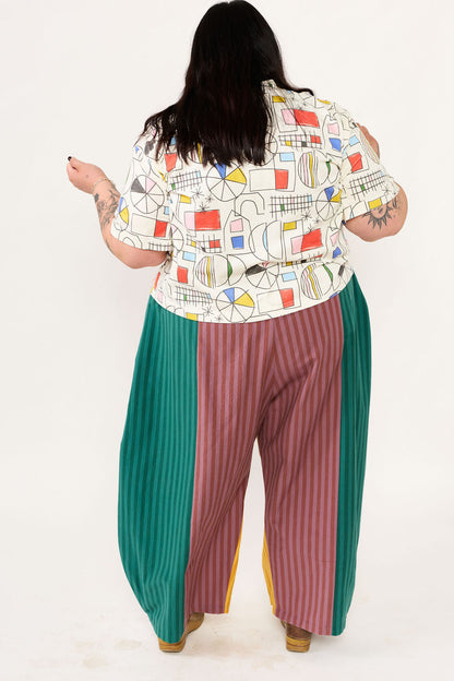 Person wearing a colorful patterned shirt and multicolored pants on a white background