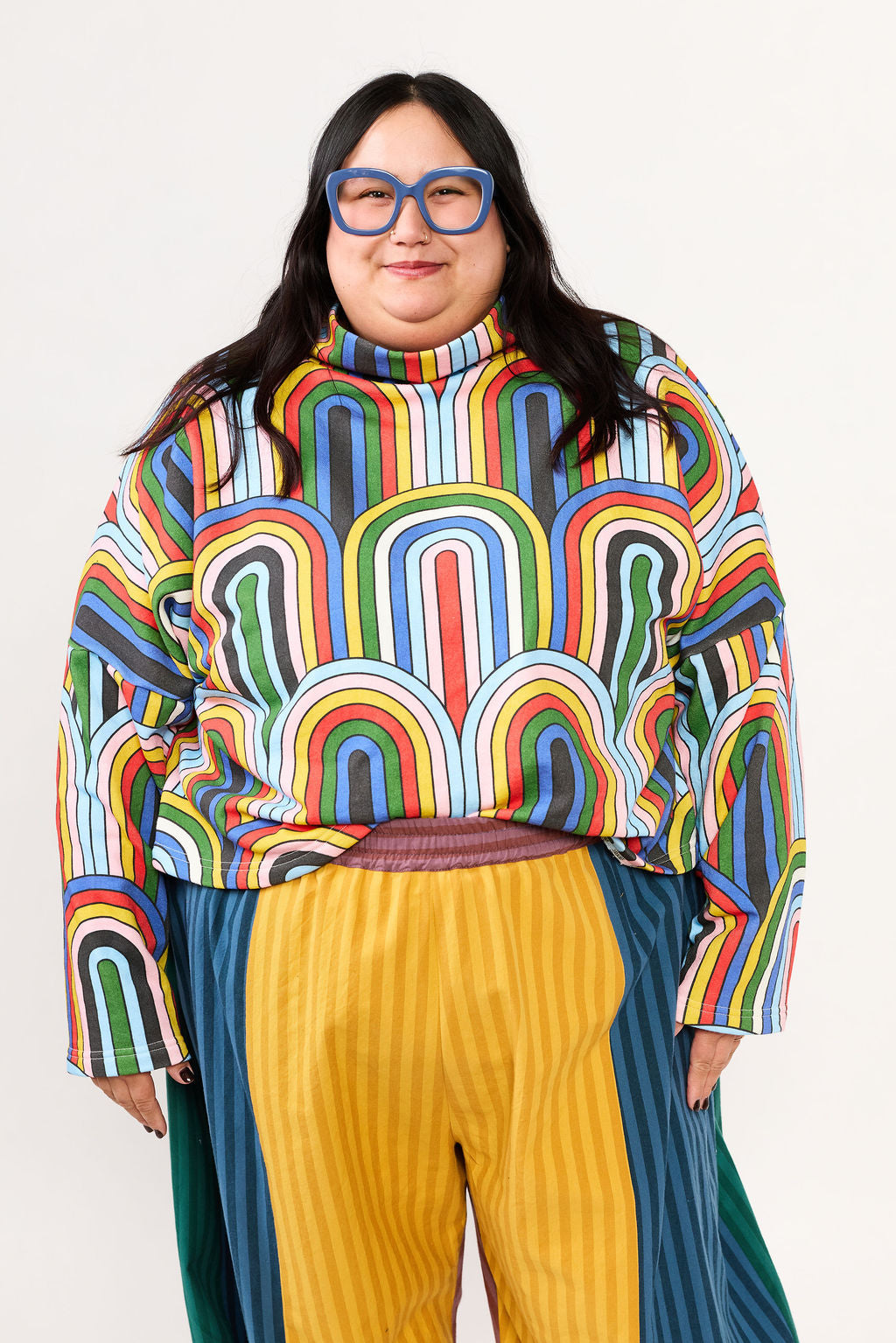 Plus size model wearing a colorful patterned sweatshirt and striped pants by Lilla Barn Clothing