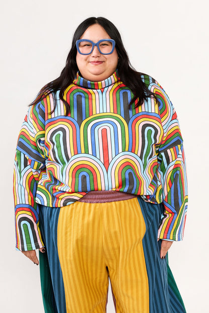 Plus size model wearing a colorful patterned sweatshirt and striped pants by Lilla Barn Clothing