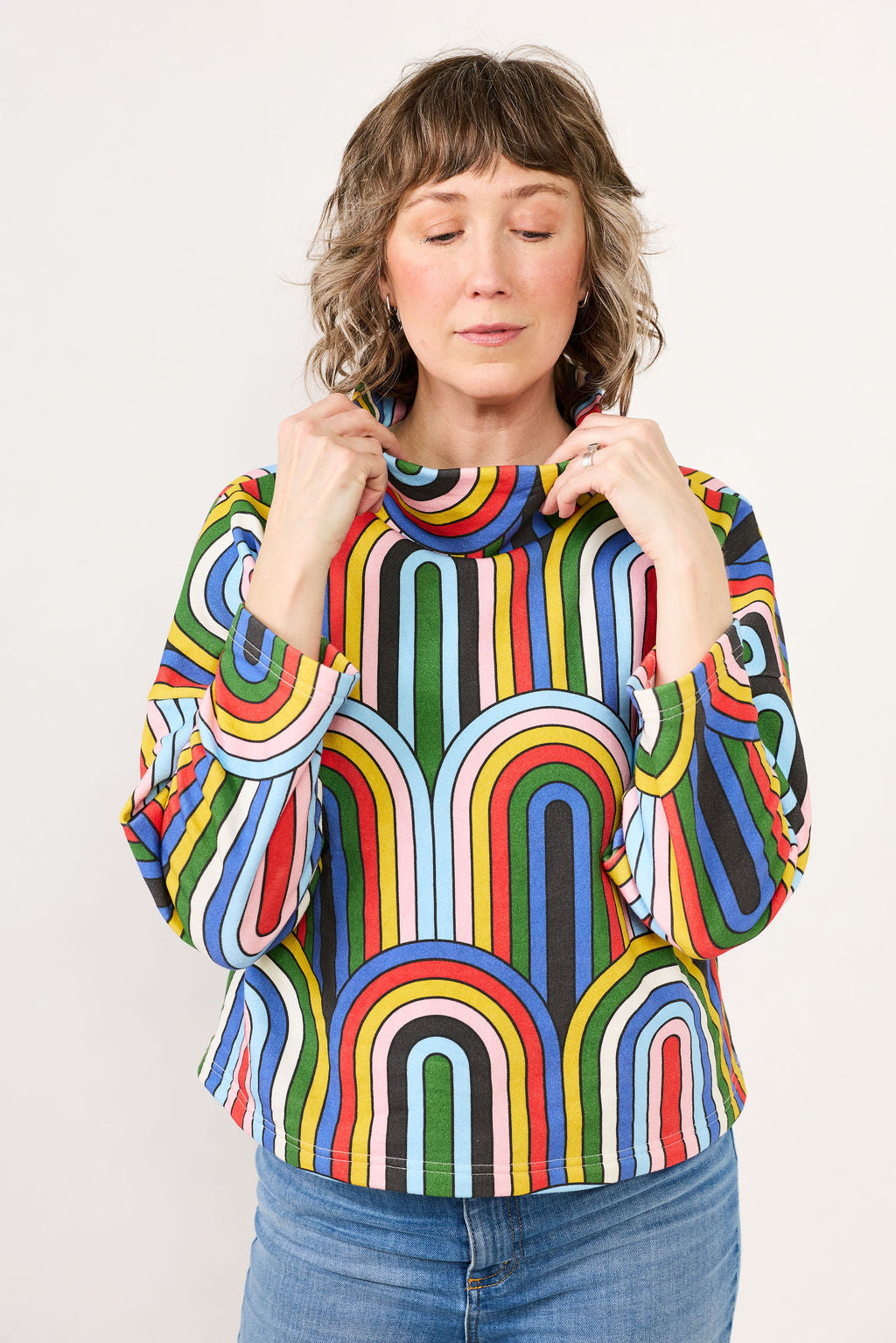Woman wearing a colorful striped sweater against a plain background