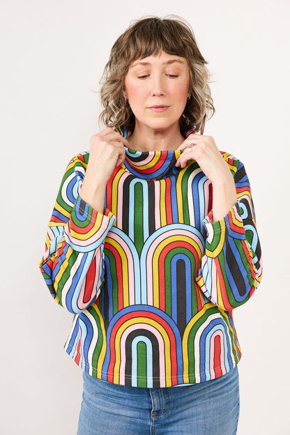 Woman wearing a colorful striped sweater against a plain background