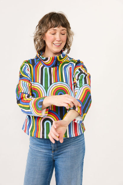 Person wearing a colorful rainbow striped shirt with a white background