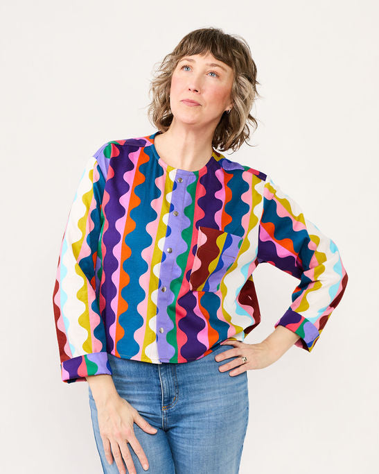 Woman wearing a colorful patterned shirt and jeans on a white background