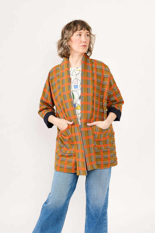 Person wearing a patterned orange and brown jacket on a white background