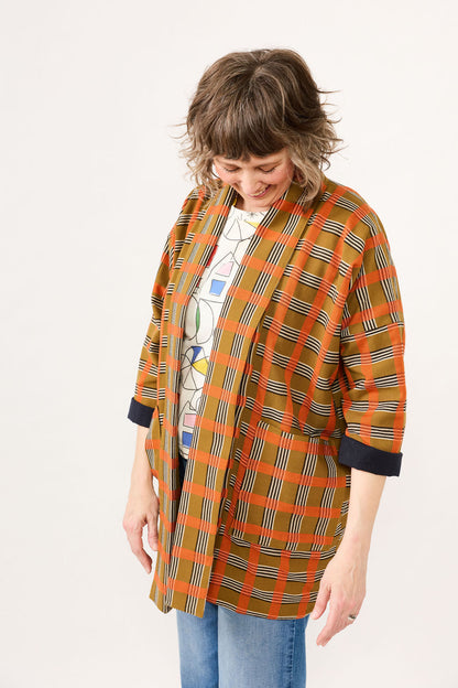 Woman wearing an orange and black plaid coat on a white background