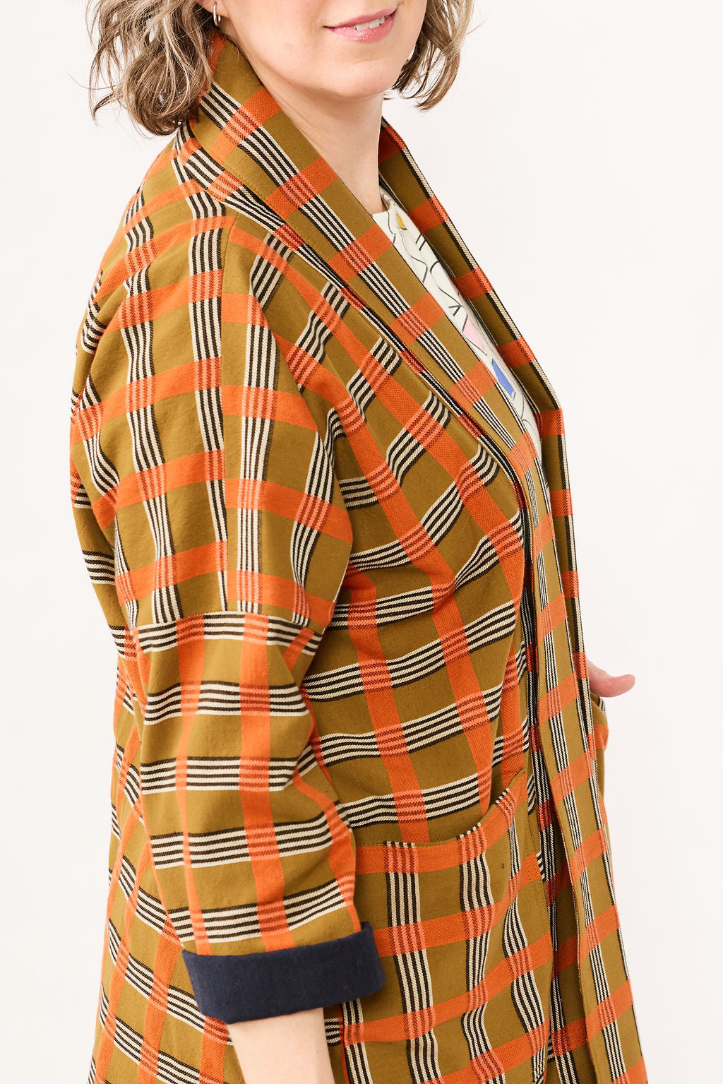 Plaid jacket with orange, brown, and black pattern on a white background