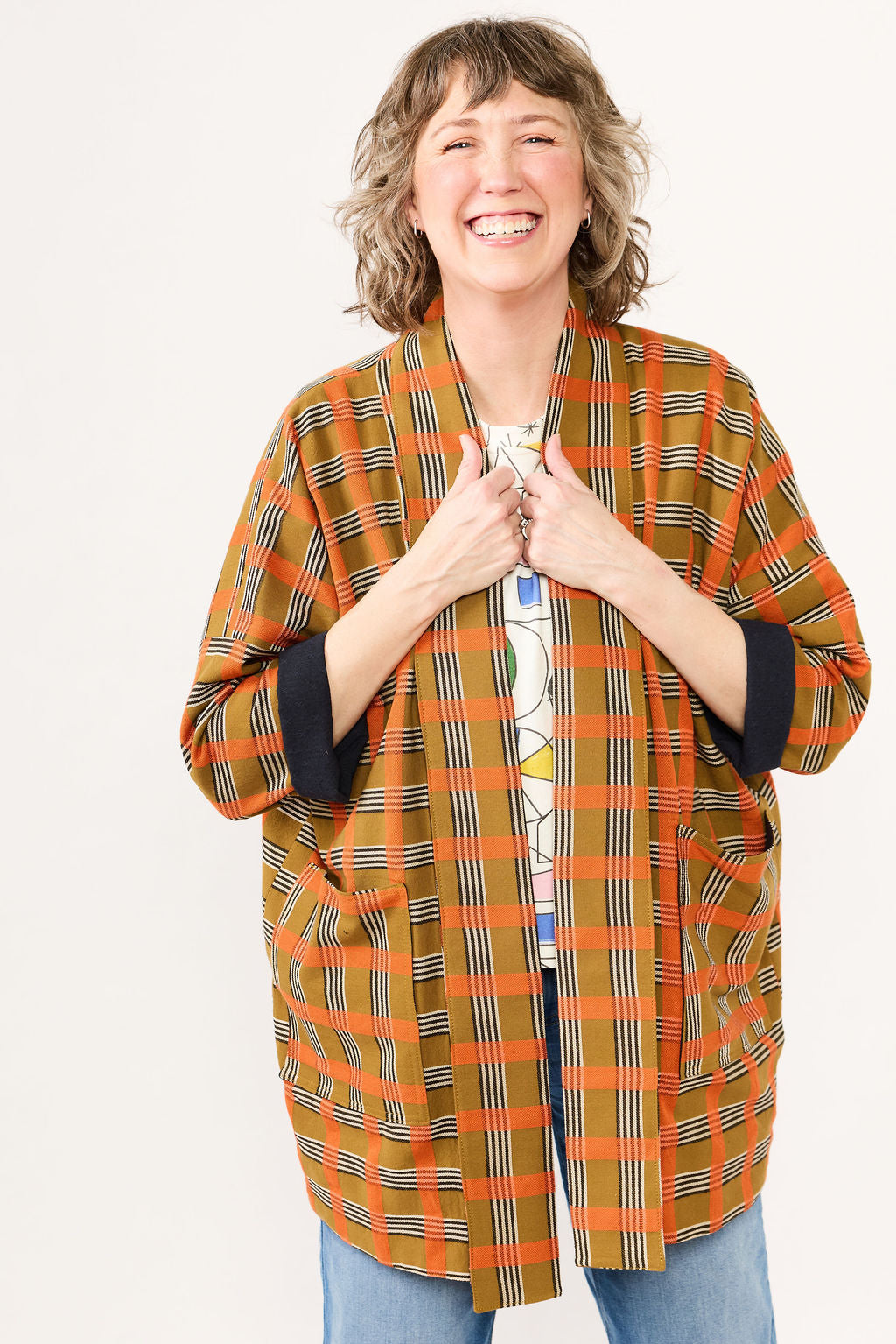 Woman wearing a plaid orange and black jacket on a white background