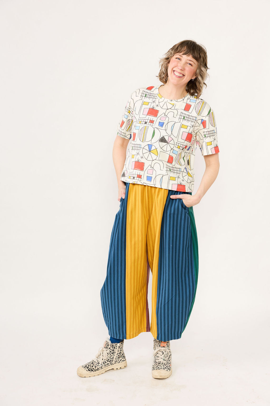 Person wearing a colorful patterned shirt and multicolored pants on a white background