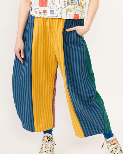Person wearing colorful striped pants and a patterned top on a white background