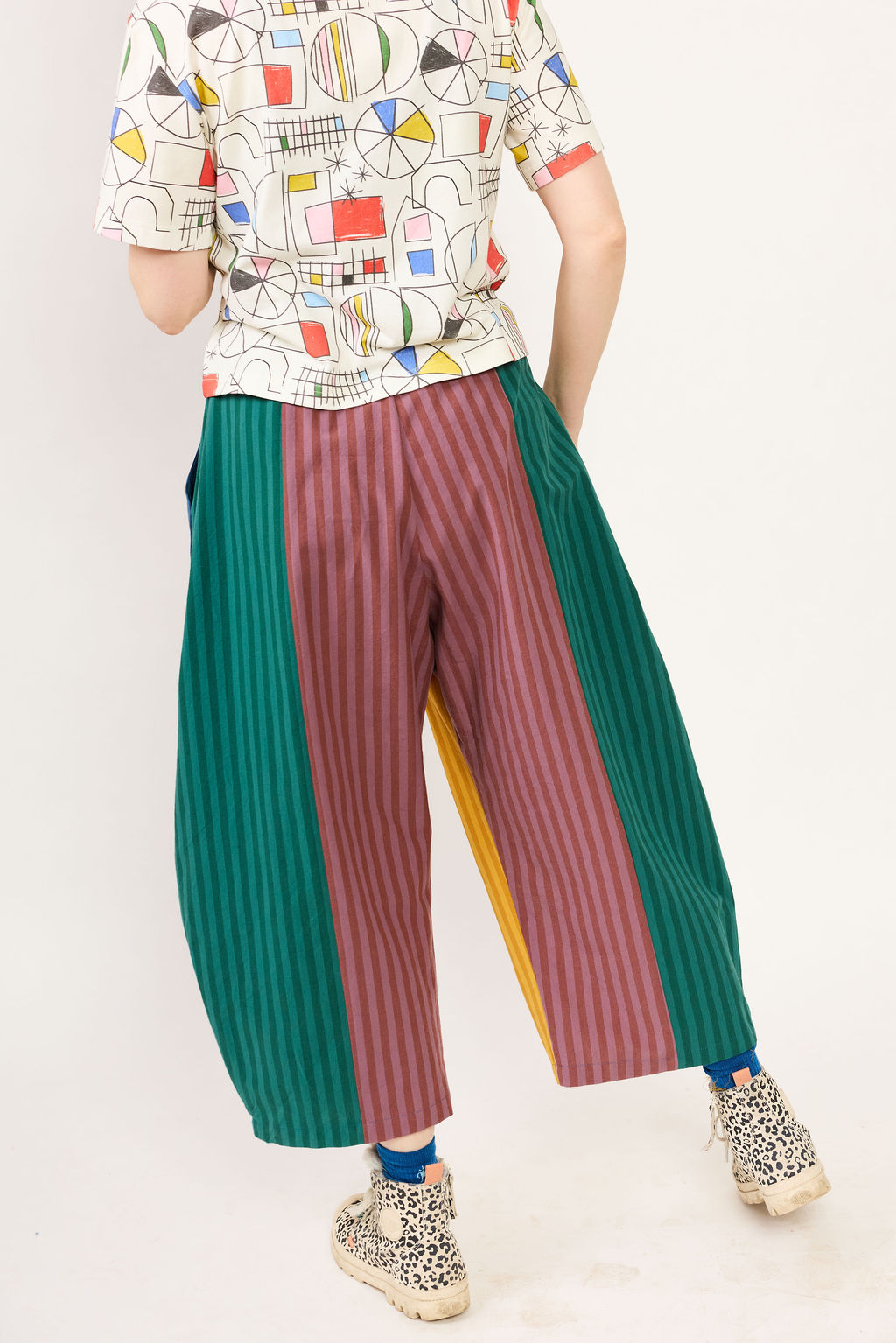 Person wearing a colorful patterned shirt and multicolored pants on a white background