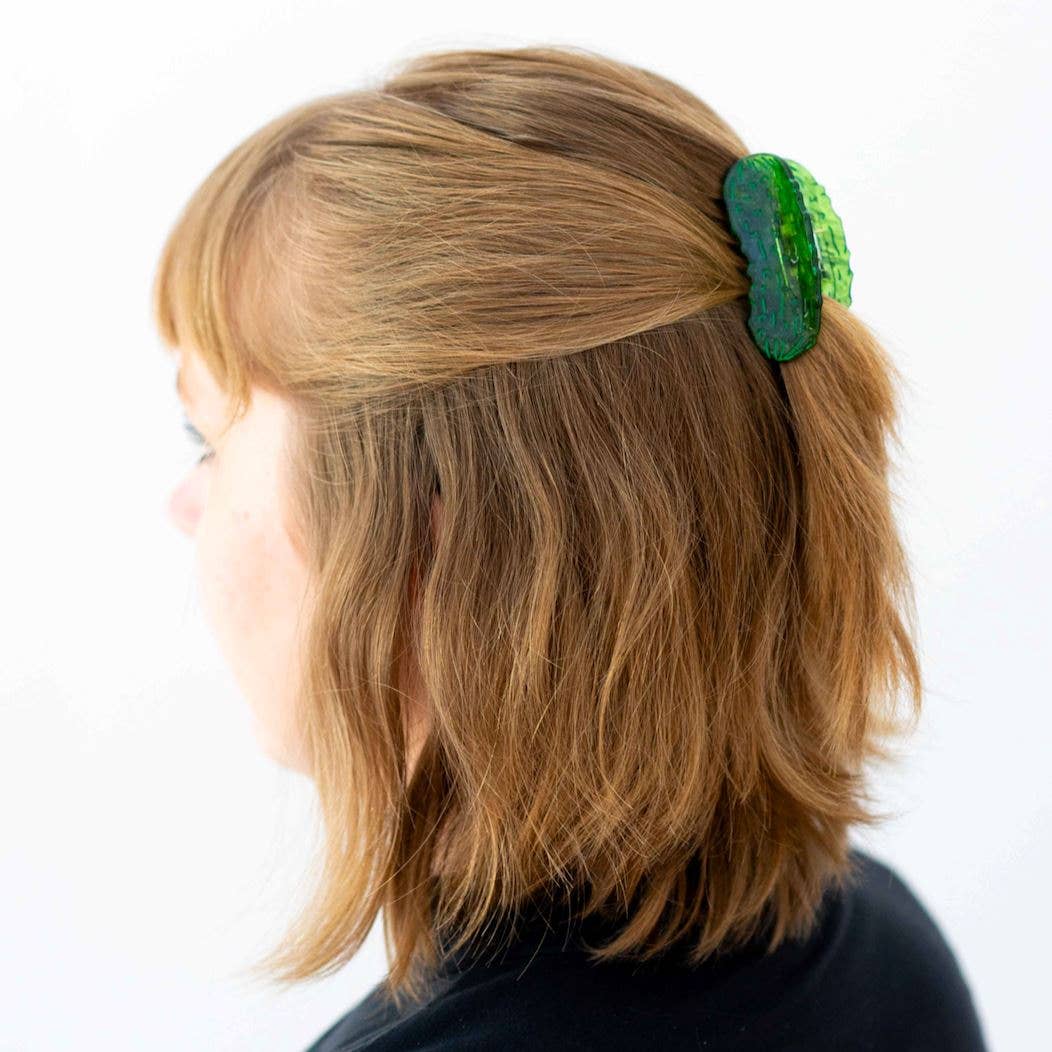 Person with a green hair pickle clip in their hair on a white background