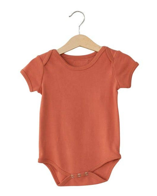 This image features a charming organic short sleeve bodysuit in a delightful peachy color. The bodysuit is displayed on a wooden hanger, emphasizing its eco-friendly qualities.