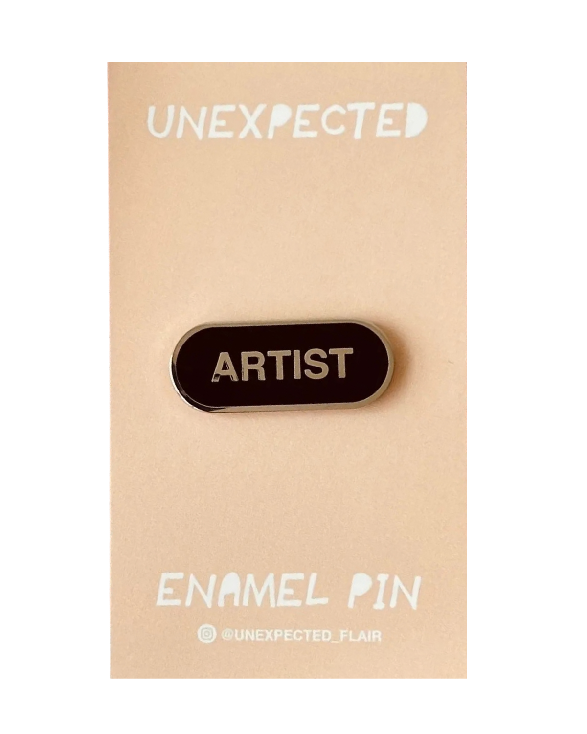 Enamel pin with 'ARTIST' text on a beige card with 'UNEXPECTED' branding.