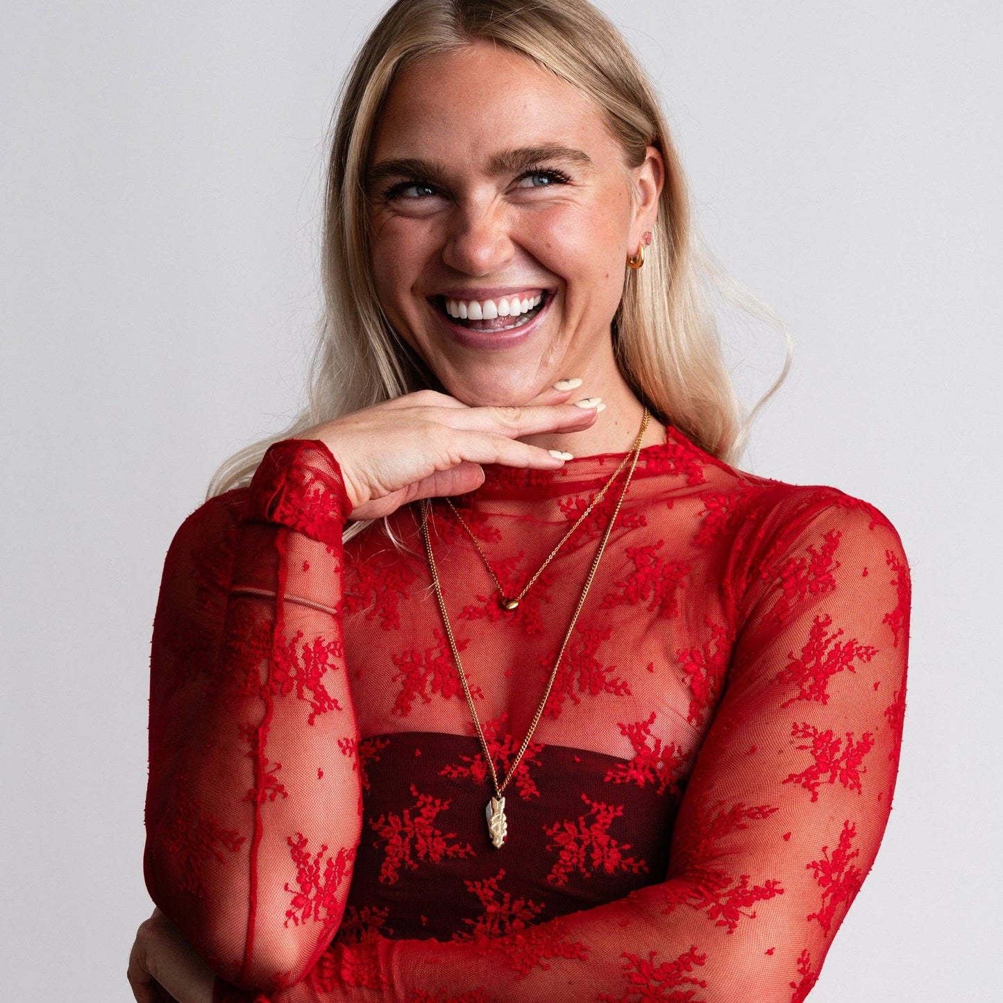 Woman wearing a red lace top with a plain background