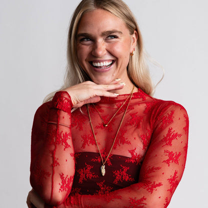 Woman wearing a red lace top with a plain background
