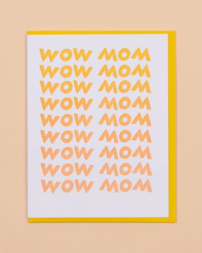 A greeting card with 'WOW MOM' text in yellow and pink gradient, displayed on a neutral background.