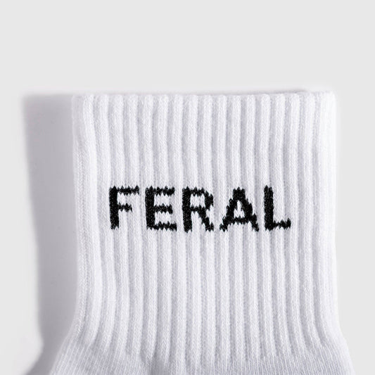 A close-up of a white ribbed knit sock with the word 'FERAL' knitted in black across the cuff, shown against a light gray background.