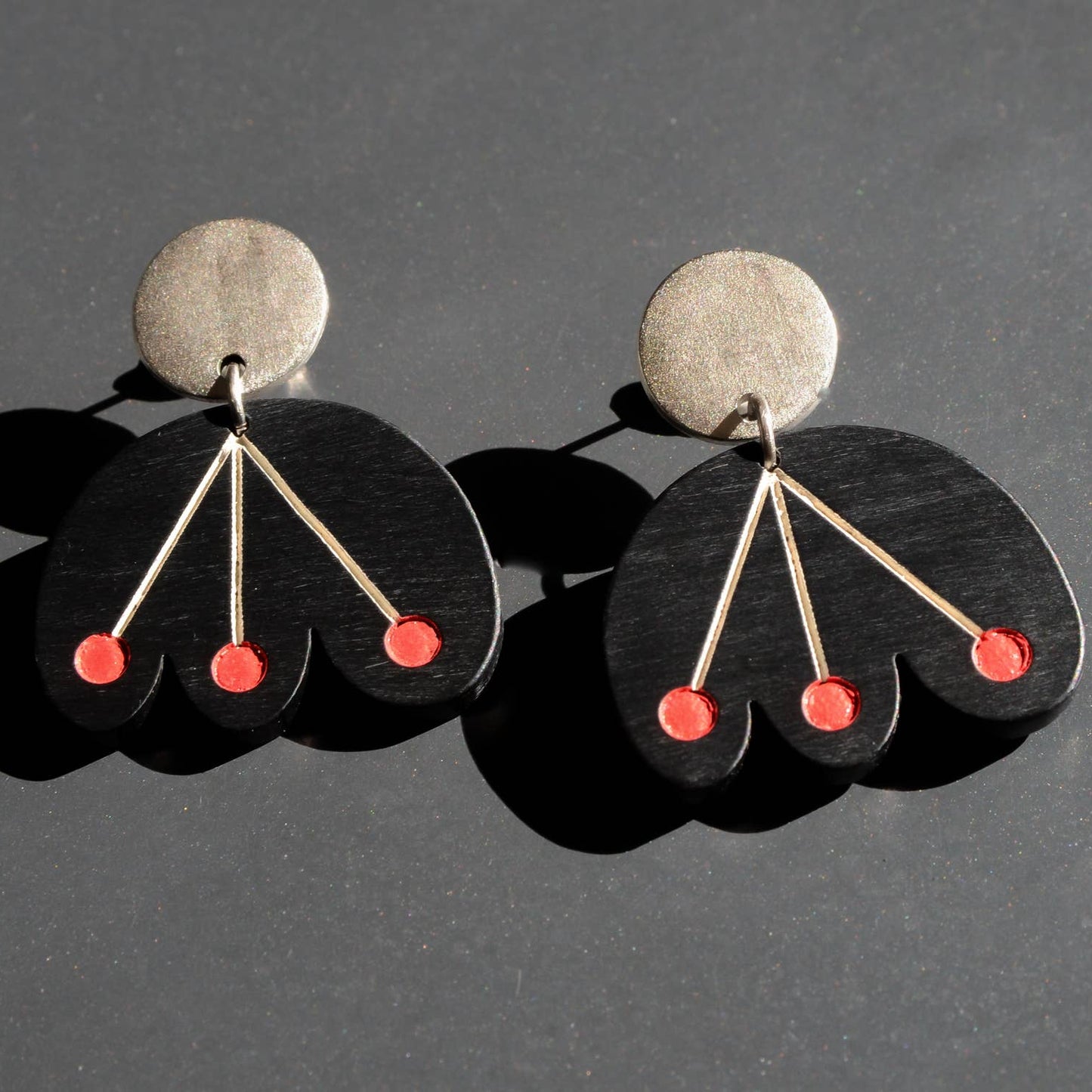 Pair of earrings with black and silver design on a dark background