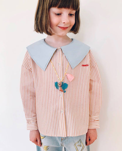 Child wearing a striped shirt with a large collar and colorful bird necklace on a plain background