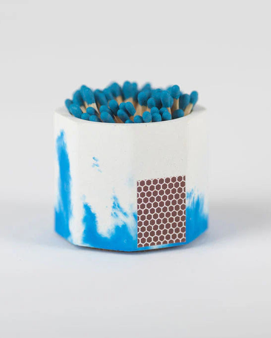 Matches in a blue and white container on a light gray background