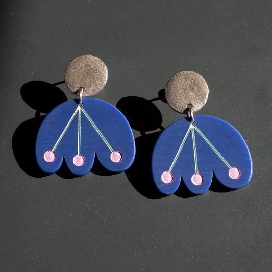 Pair of blue earrings with pink accents on a dark background