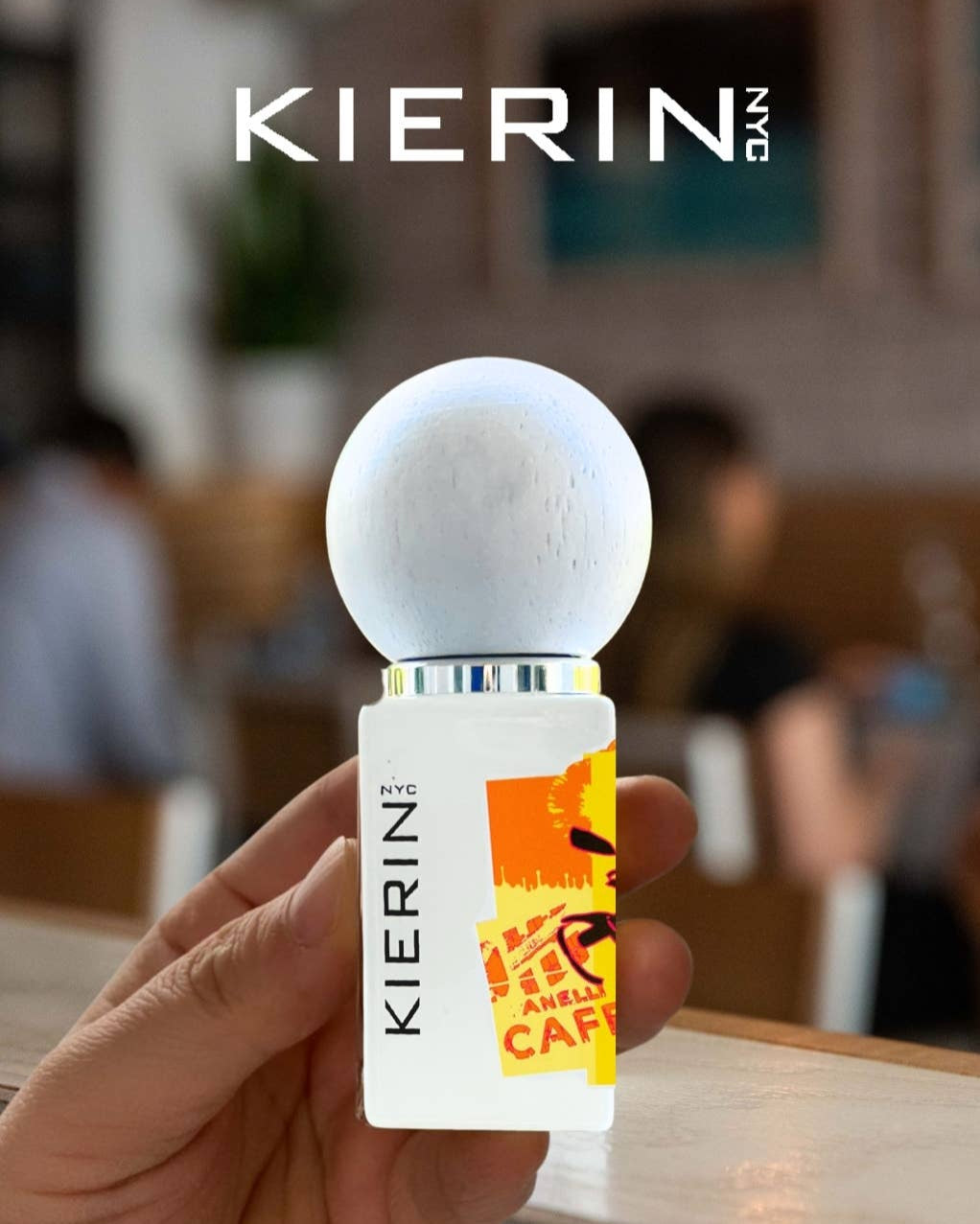 Hand holding a Kierin can with a blurred indoor background