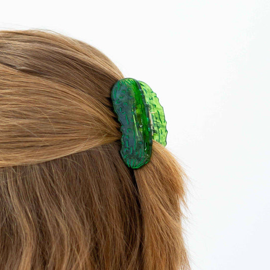 Green pickle hair clip in a person's hair on a white background
