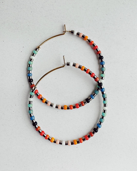 Set of colorful beaded hoop earrings on gold-fill wire on a light gray background
