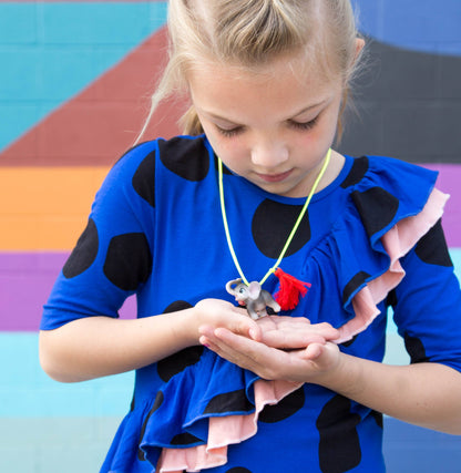 Young child holding a small elephant necklace with colorful background