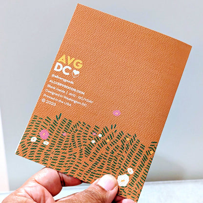 back side of a greeting card with floral design held by a hand against a light gray background