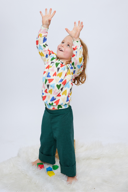 toddler standing with arms up wearing green cuffed sustainable pants