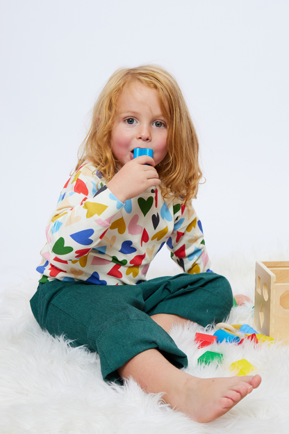 boy with long hair playing with blocks and wearing colorful gender-neutral clothes
