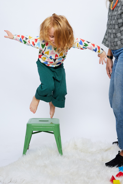 boy with long hair jumping wearing comfortable and colorful clothing