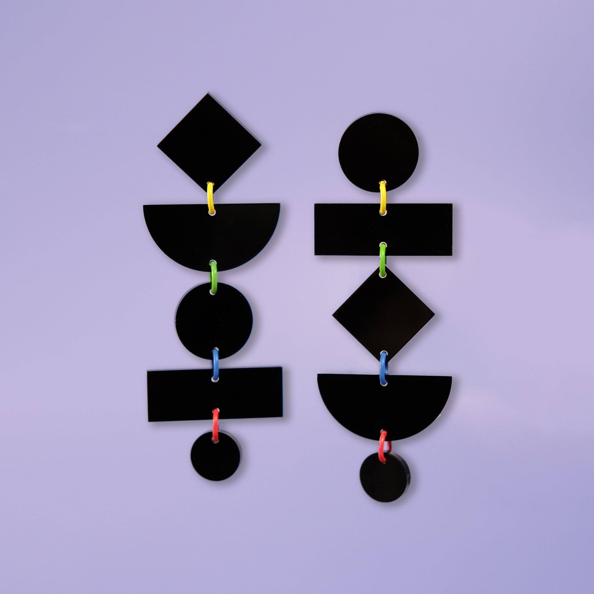Black geometric earrings on a purple background