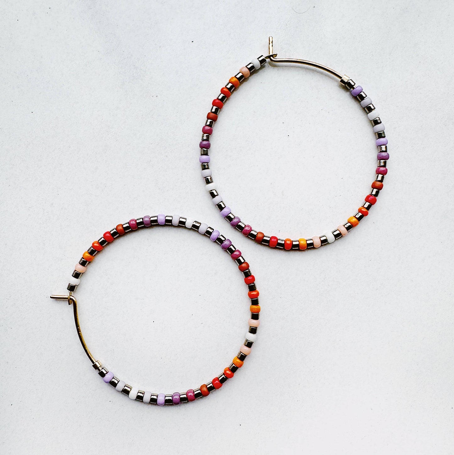 Colorful beaded hoop earrings on a light gray background