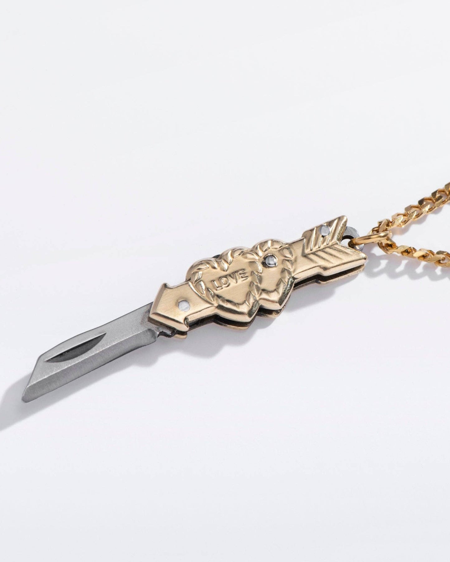 Gold necklace with a dagger pendant on a white background