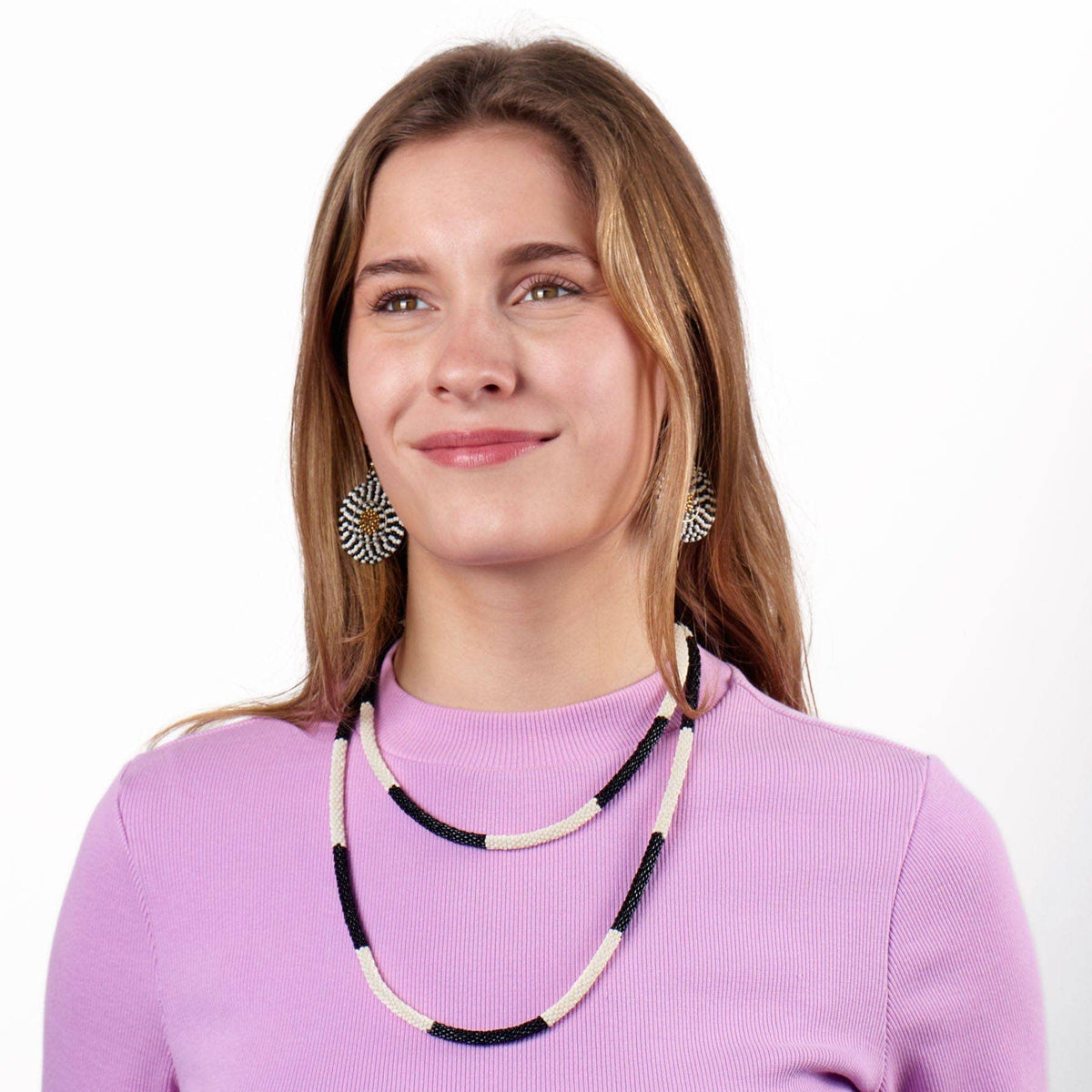 Woman wearing a black and white beaded necklace and earrings on a white background