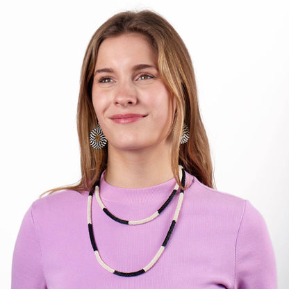 Woman wearing a black and white beaded necklace and earrings on a white background