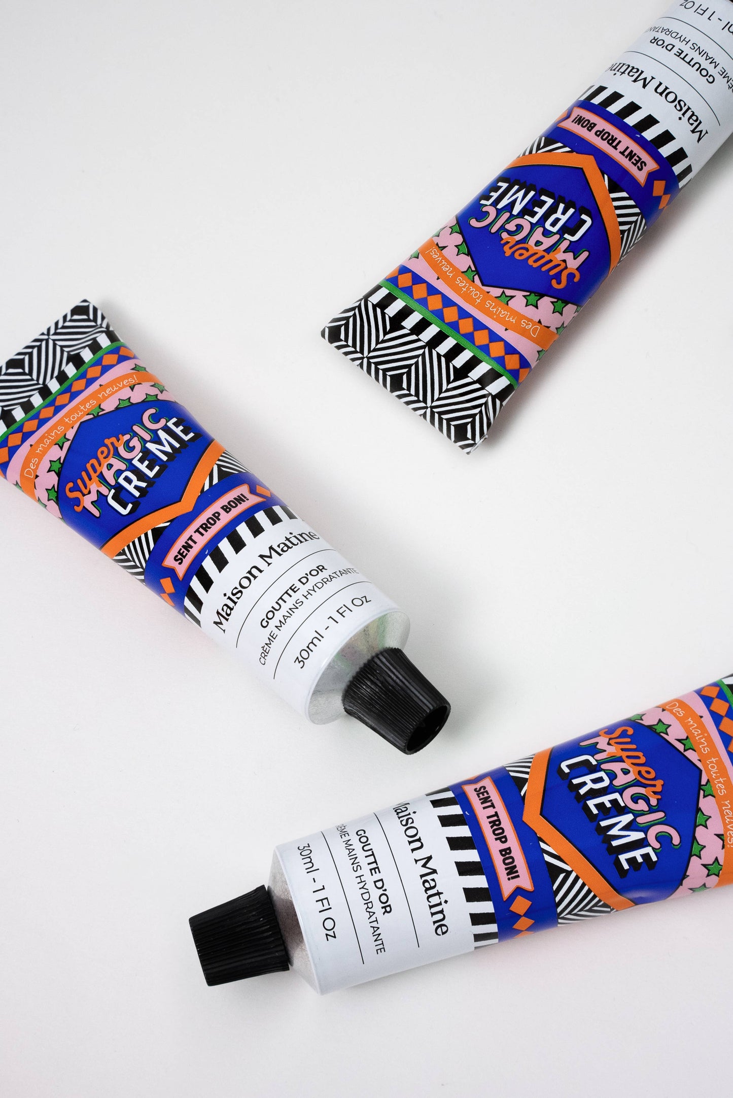Three tubes of Super Creme Hand Creme by Maison Matine with colorful packaging on a white background