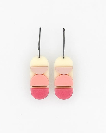 A pair of ombre color earrings in mauve, pink, and peony shades with a metallic line shimmering between them, made of reclaimed acrylic materials, resembling a stone-like texture, and finished with handmade oxidized silver hooks.