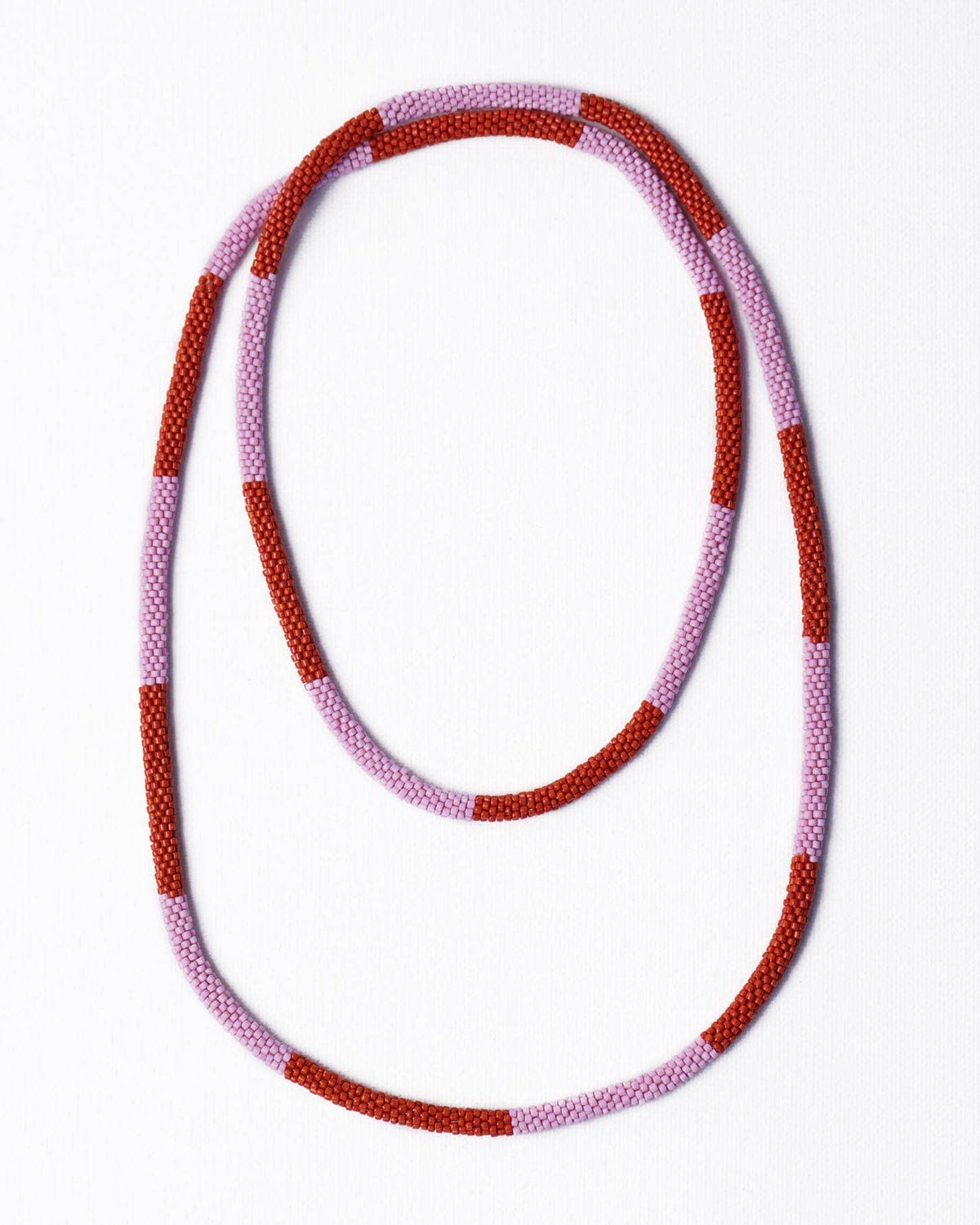 A beaded necklace with alternating textured red and light pink beads, arranged in a loose loop on a clean white background.