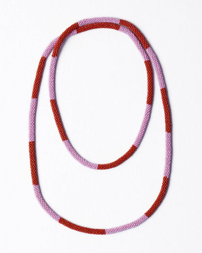 A beaded necklace with alternating textured red and light pink beads, arranged in a loose loop on a clean white background.