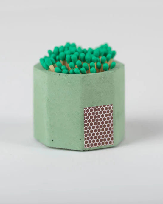 Green concrete match holder with matches on a white background