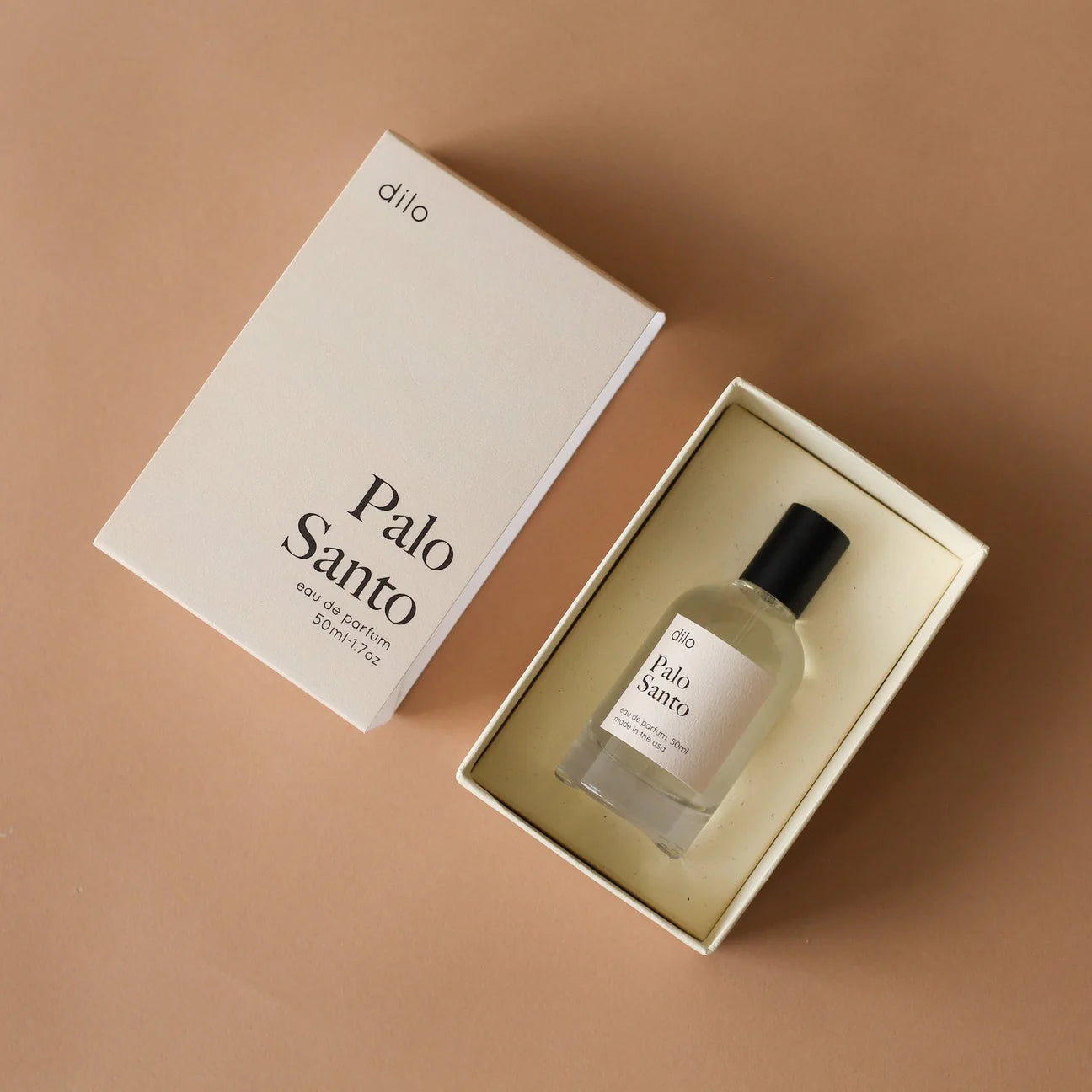 Perfume bottle labeled 'Palo Santo' by 'dilo' in an open box on a brown background