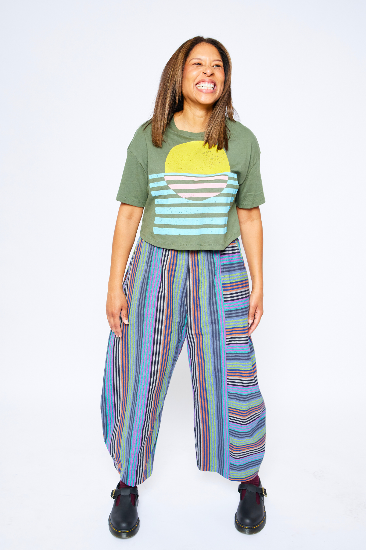 woman standing and laughing contagiously. she's wearing a hand-printed tshirt by earth cadets and sustainable and colorful pants