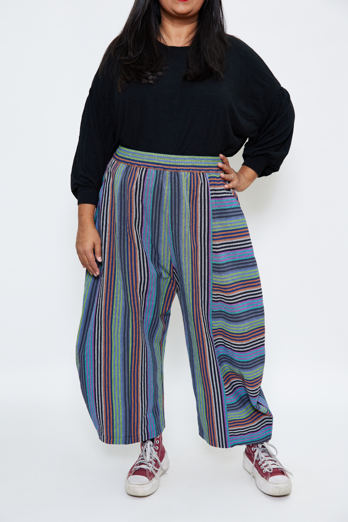 woman standing with one hand on her hip. She's confident and strong wearing striped barrel-leg cotton pants made sustainably in Chicago