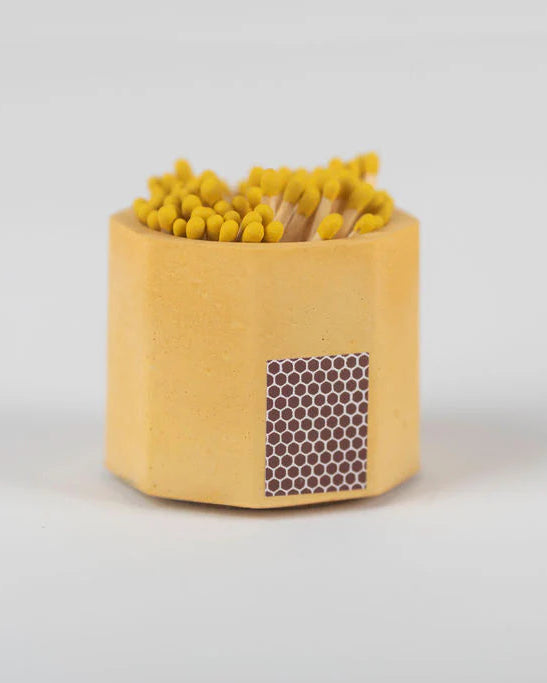 Yellow concrete match holder with matches on a white background